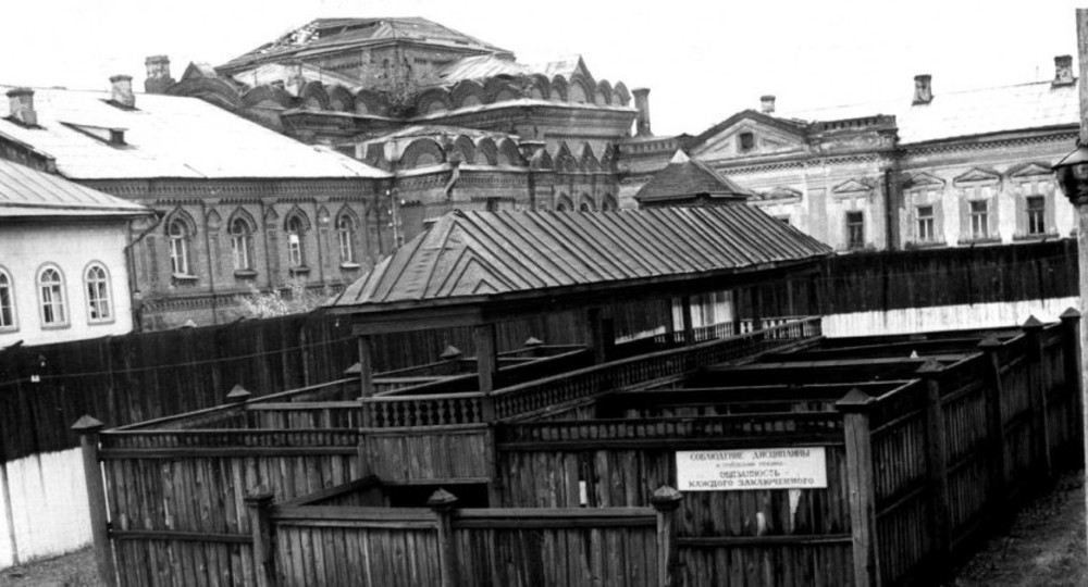 Зона для прогулок. На стене надпись: "Соблюдение дисциплины и требований охраны — обязанность каждого заключённого". <br/>На втором плане — обезглавленная Всехскорбященская церковь.